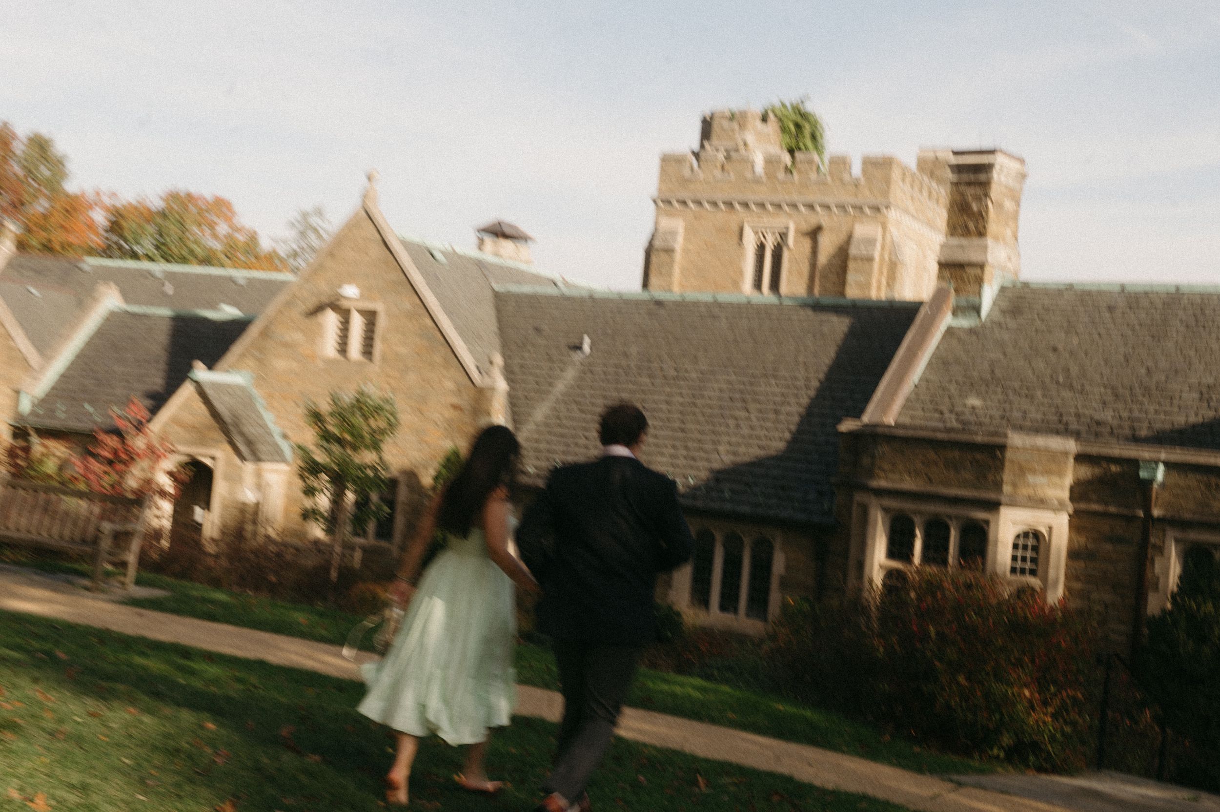 A row of stone Gothic revival buildings with peaked roofs and architectural details shown in a panoramic view.