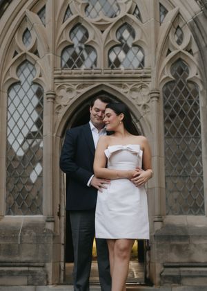 A couple shares intimate moments in front of ornate gothic windows during their wedding photoshoot.