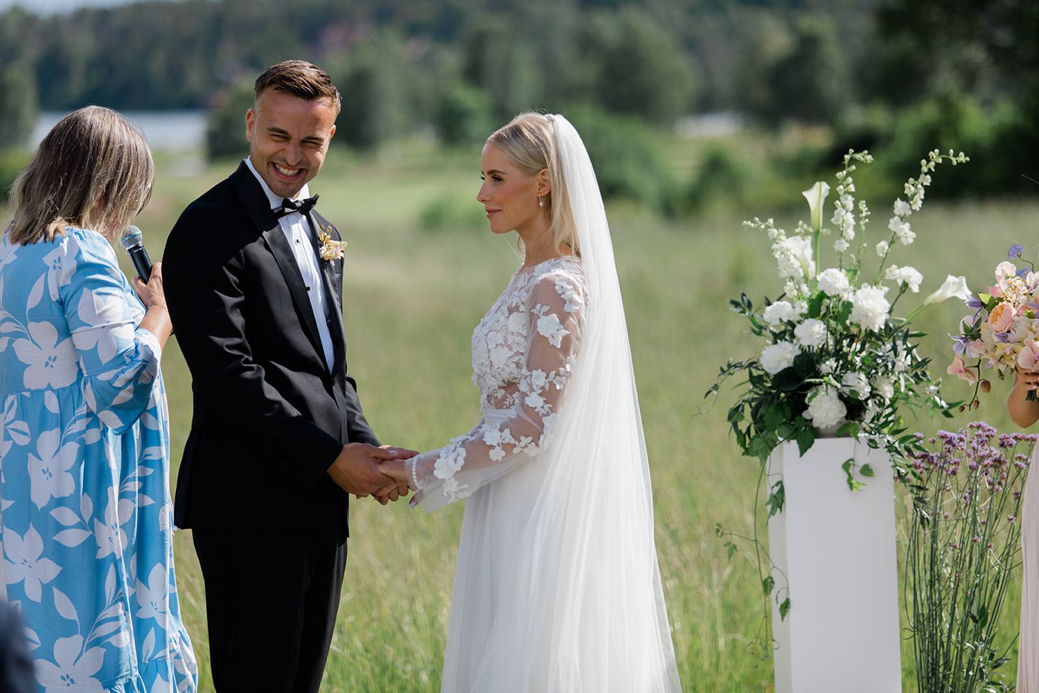 Elegant wedding couple shares romantic moments in a lush green meadow with delicate white wildflowers.