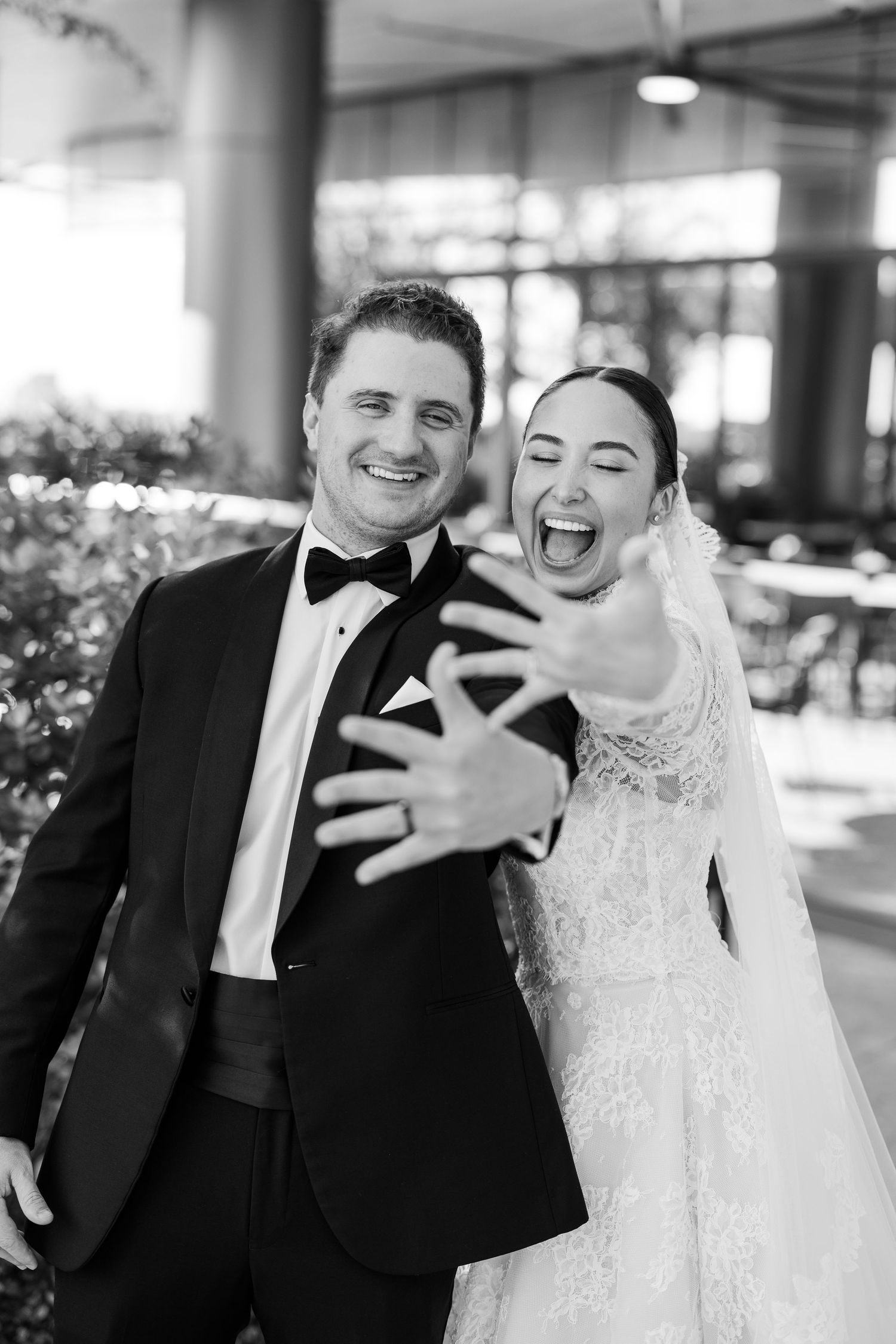 A joyful couple in wedding attire shares candid laughter during their photo session.