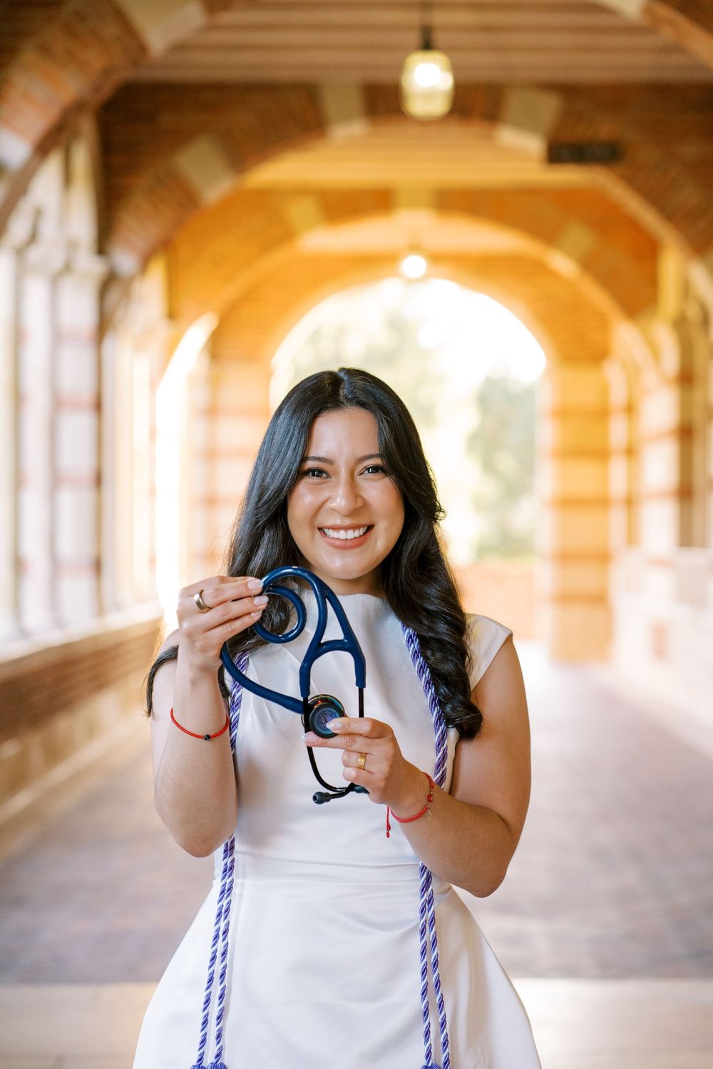 A person in a white dress poses playfully in a sunlit archway corridor, creating a series of candid expressions.