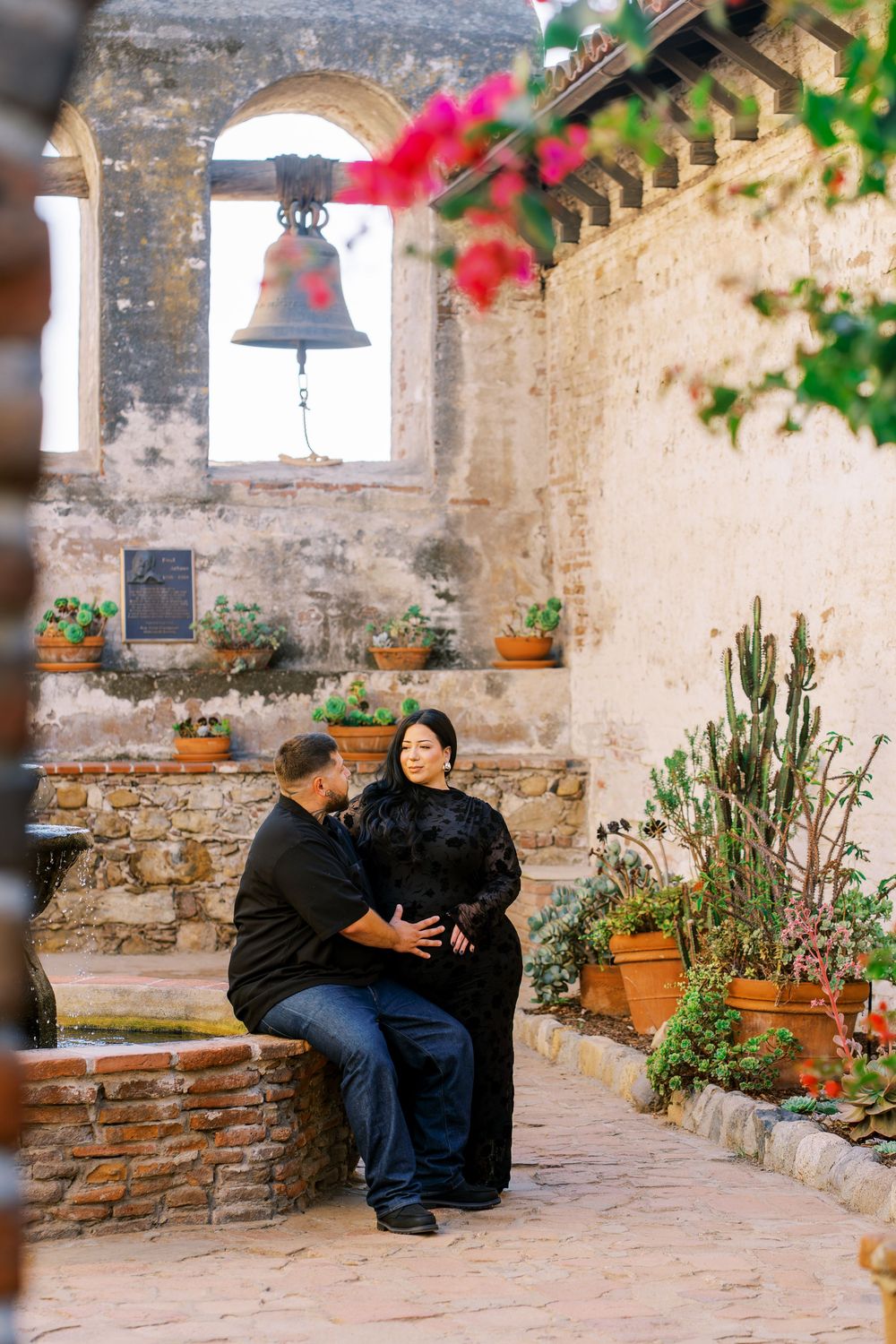 A romantic proposal scene unfolds in a rustic stone courtyard with potted plants and arched windows.