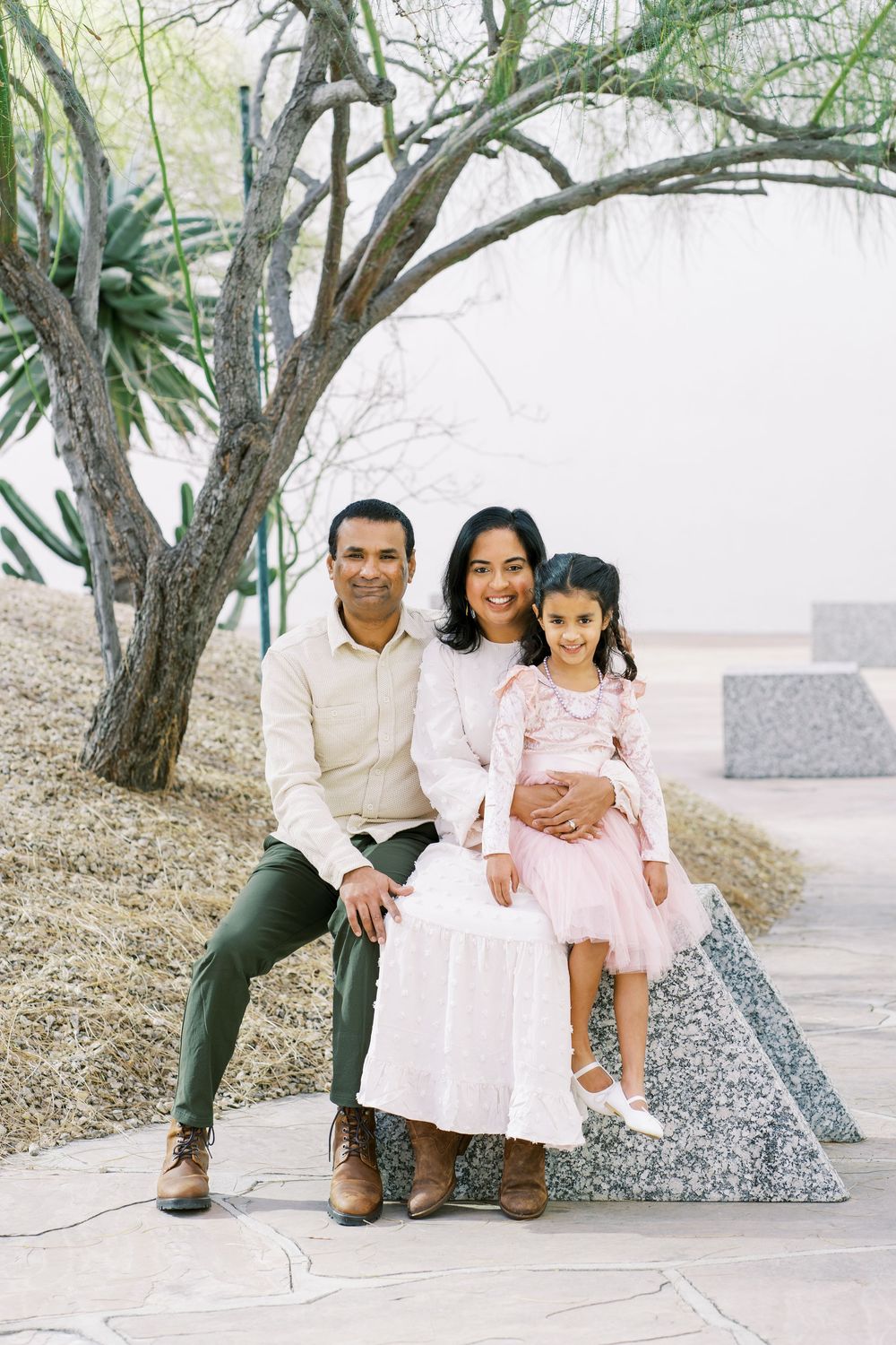 Family members sit together outdoors on stone steps surrounded by trees in a natural setting.