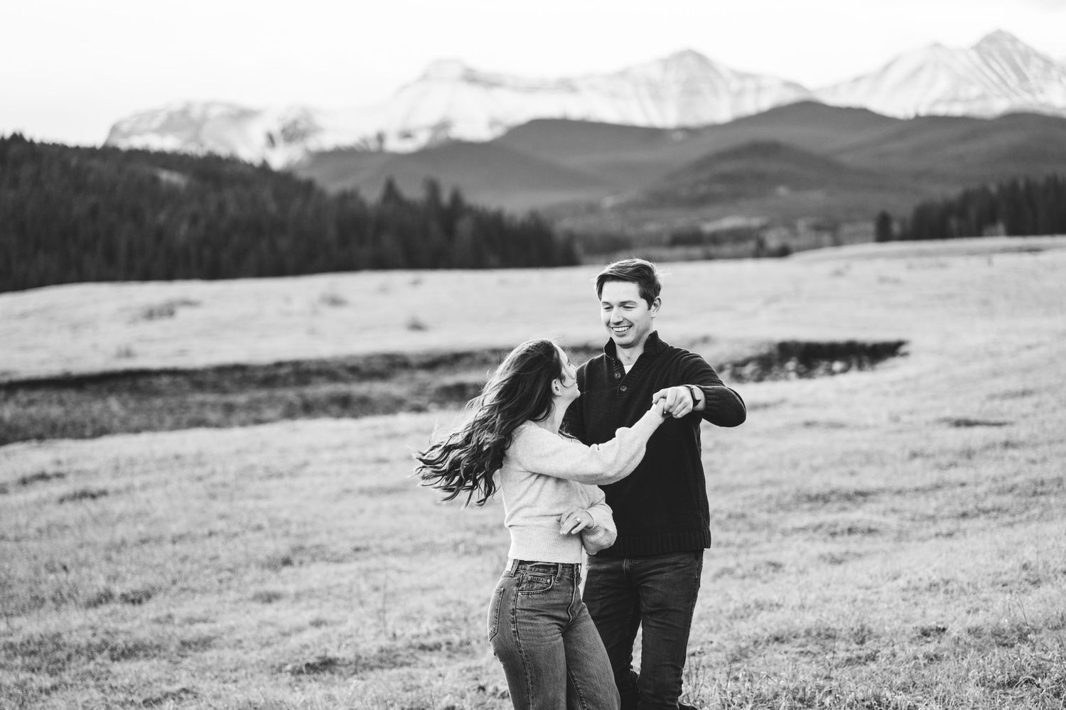 Playful couple photographs in black and white against mountain backdrop.