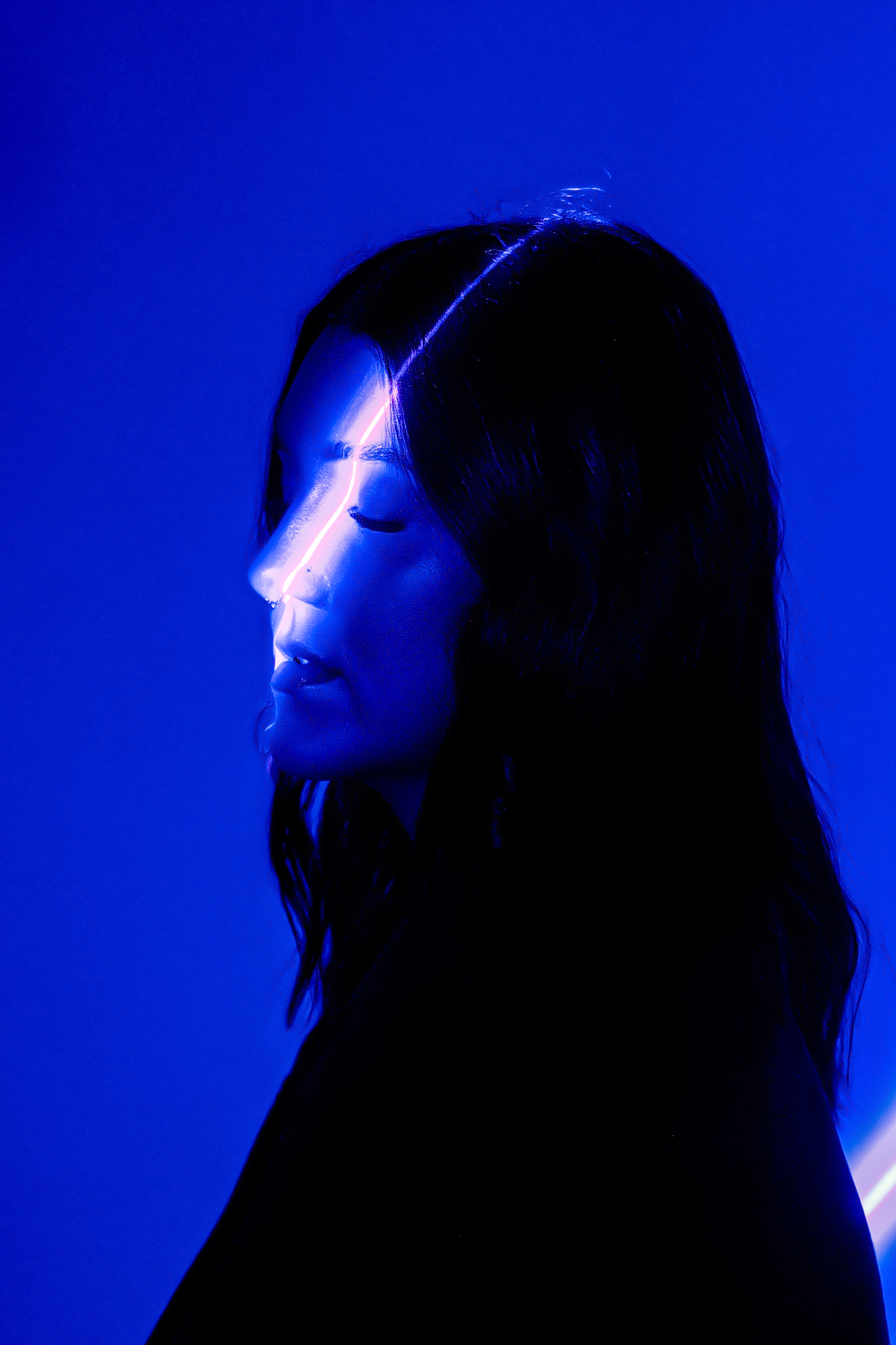 A silhouetted figure's profile against a vibrant blue background with dramatic lighting effects creating a glowing outline.