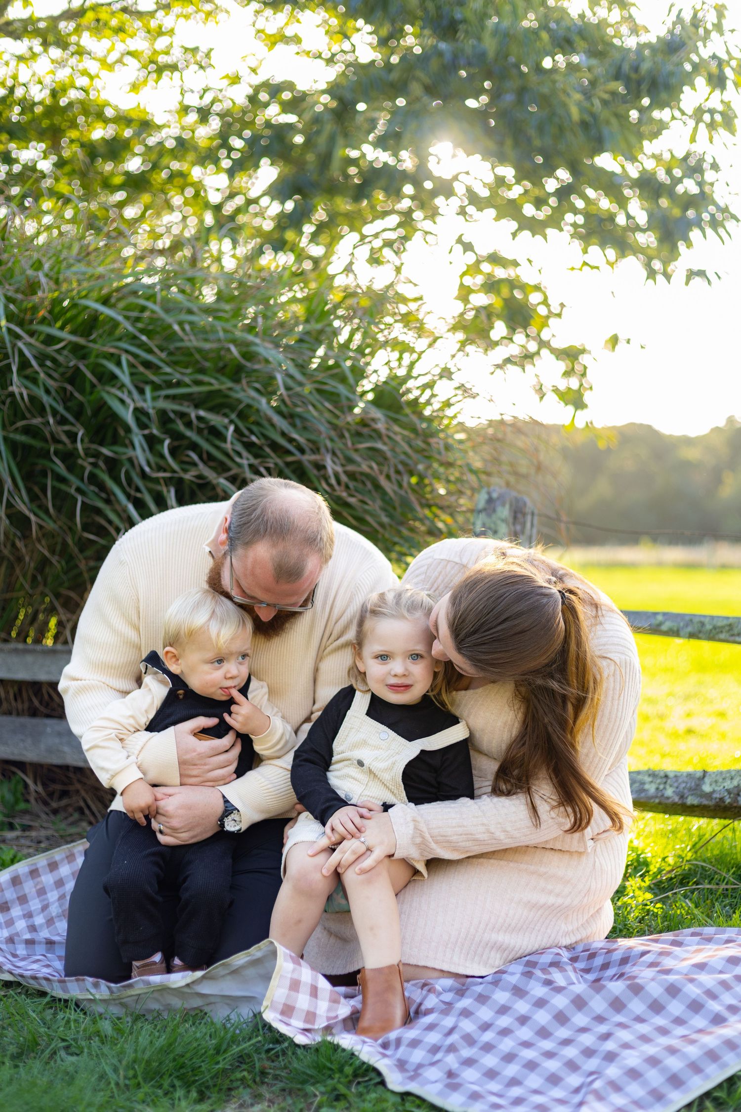 Family enjoying autumn colors while sitting together on fallen logs in a scenic forest setting.