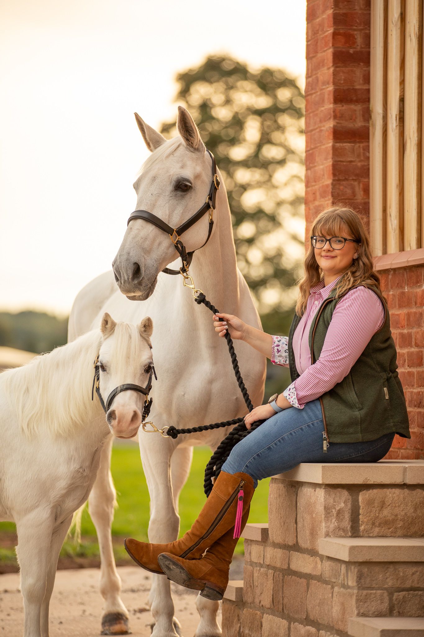 A young boy in a white shirt shares a tender moment hugging and bonding with a brown horse in a stable.