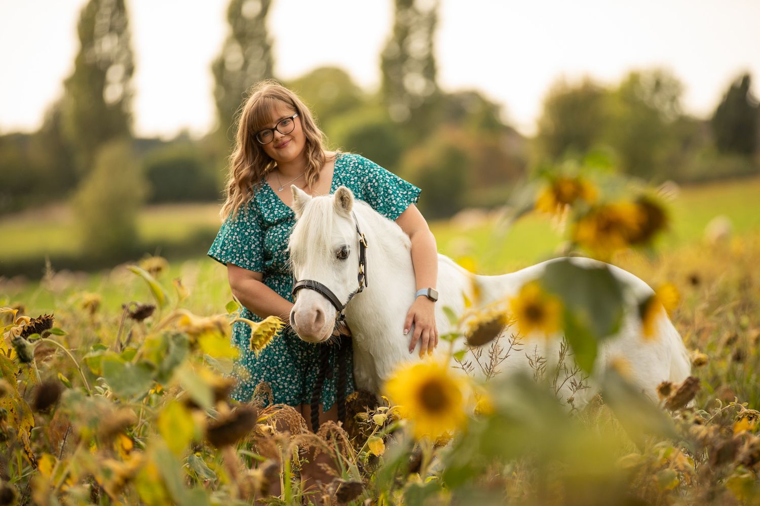 A horse and its rider enjoy an outdoor photoshoot session near rustic wooden fencing on a sunny day.