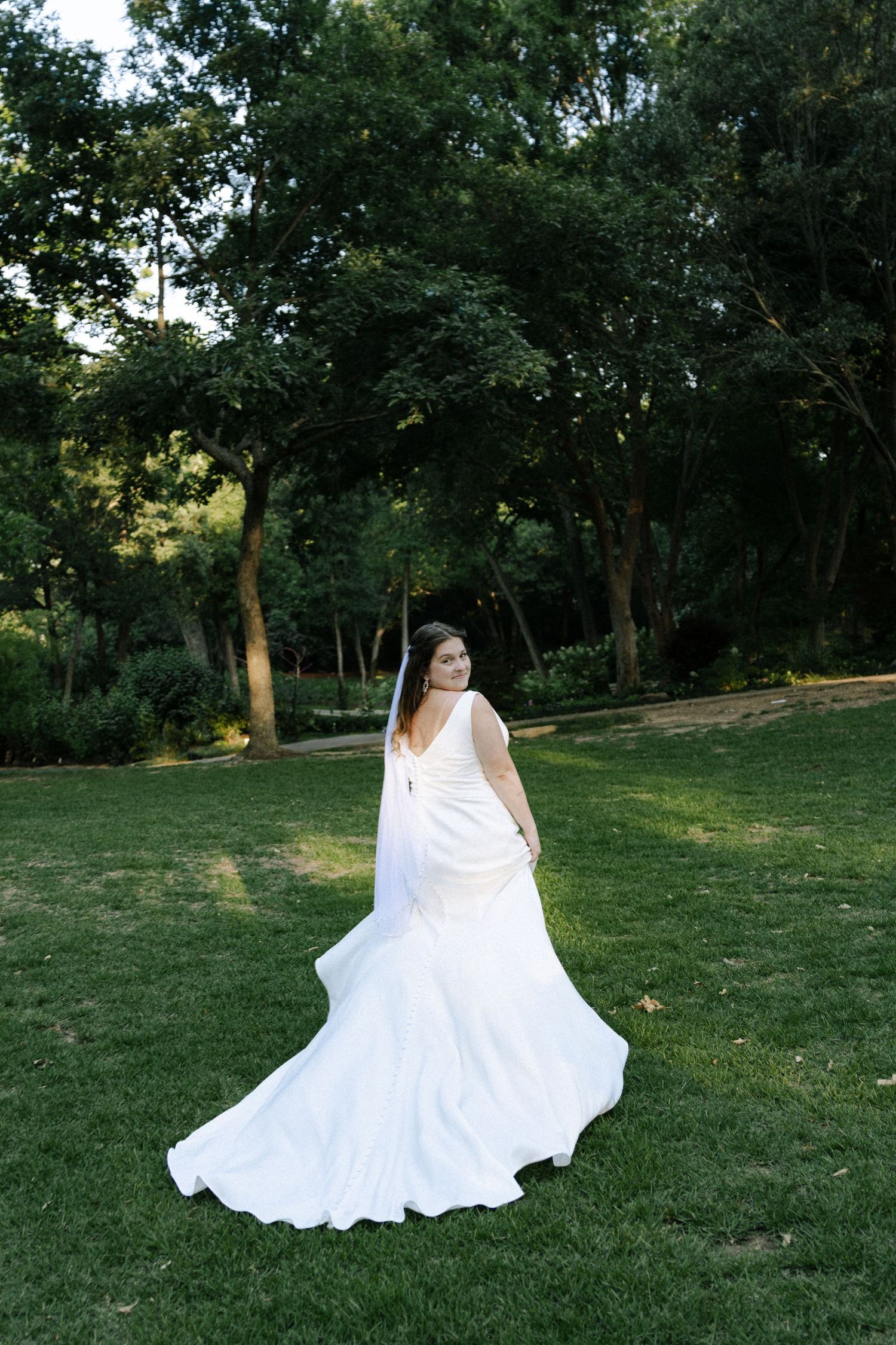 A black and white portrait of someone lying in a field of tall grass wearing a white dress.