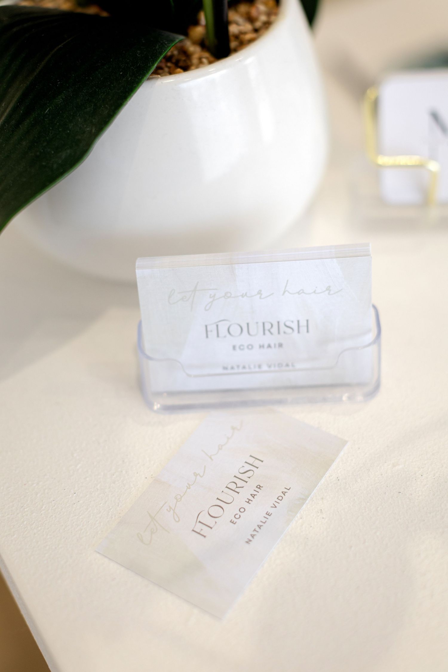 Close-up photos of elegant white business cards Flourish Eco Salon