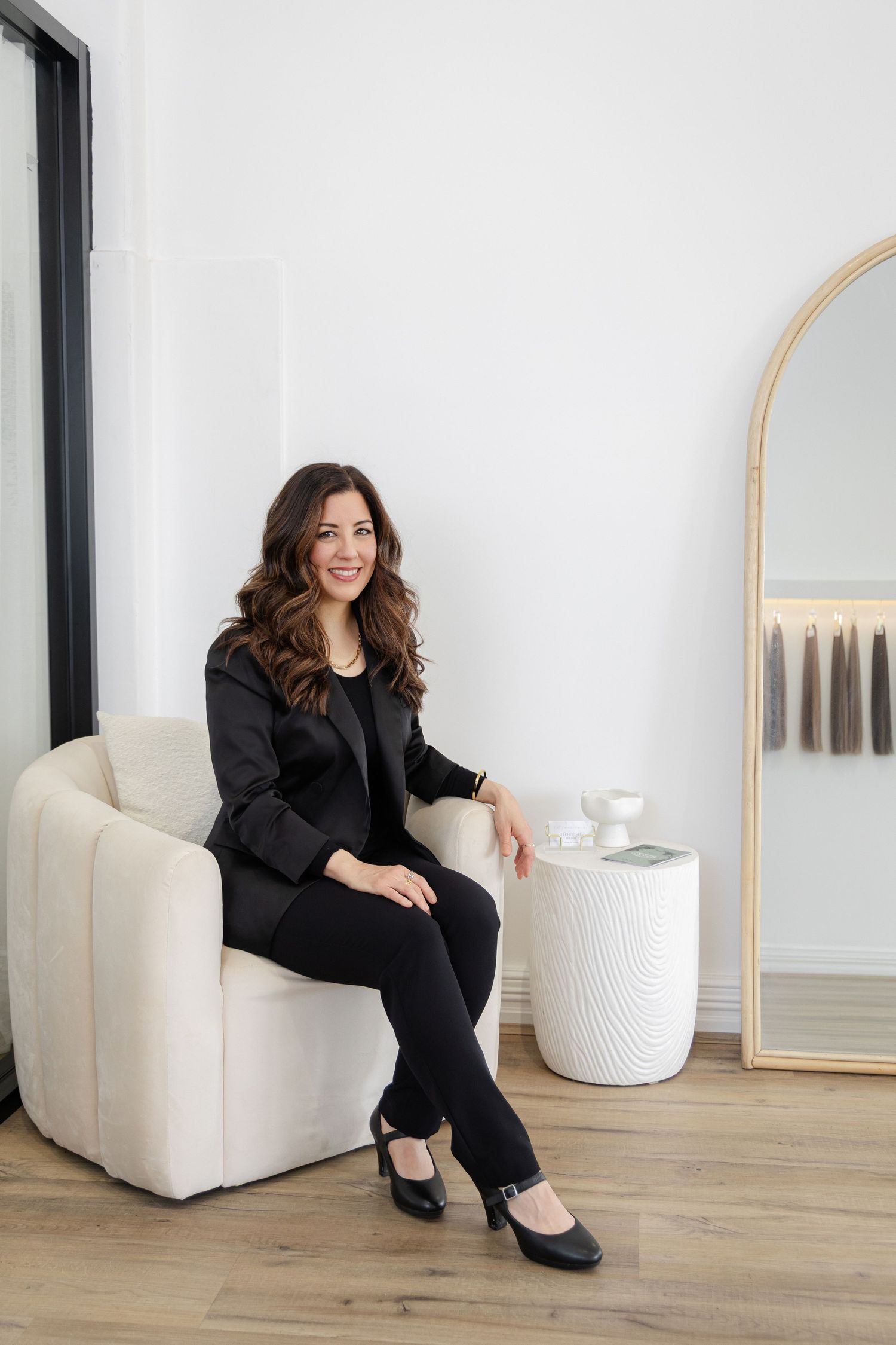 Business portraits of hair stylist and owner of Flourish salon, Natalie leans casually in modern chair smiling at camera