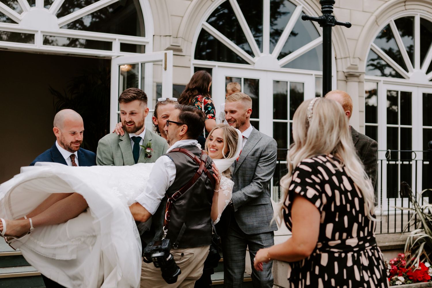 Wedding guests dance and celebrate together during a lively reception on a dance floor.