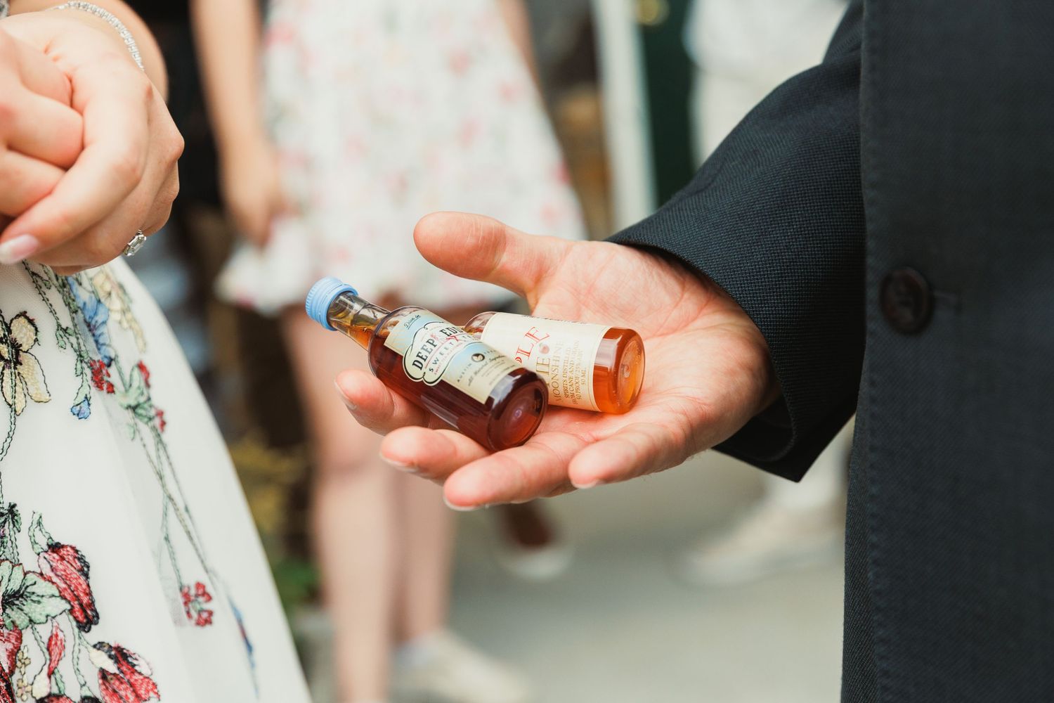 Close-up of hands exchanging wedding rings during an outdoor ceremony.