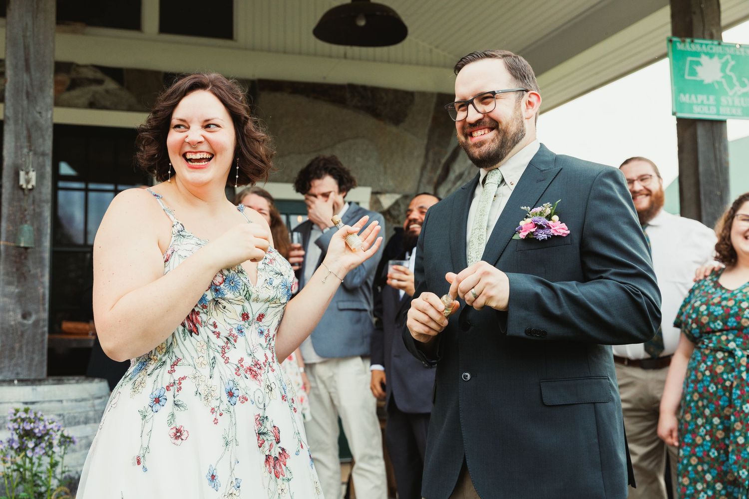 Joyful wedding reception gathering with guests laughing and socializing on a covered porch.
