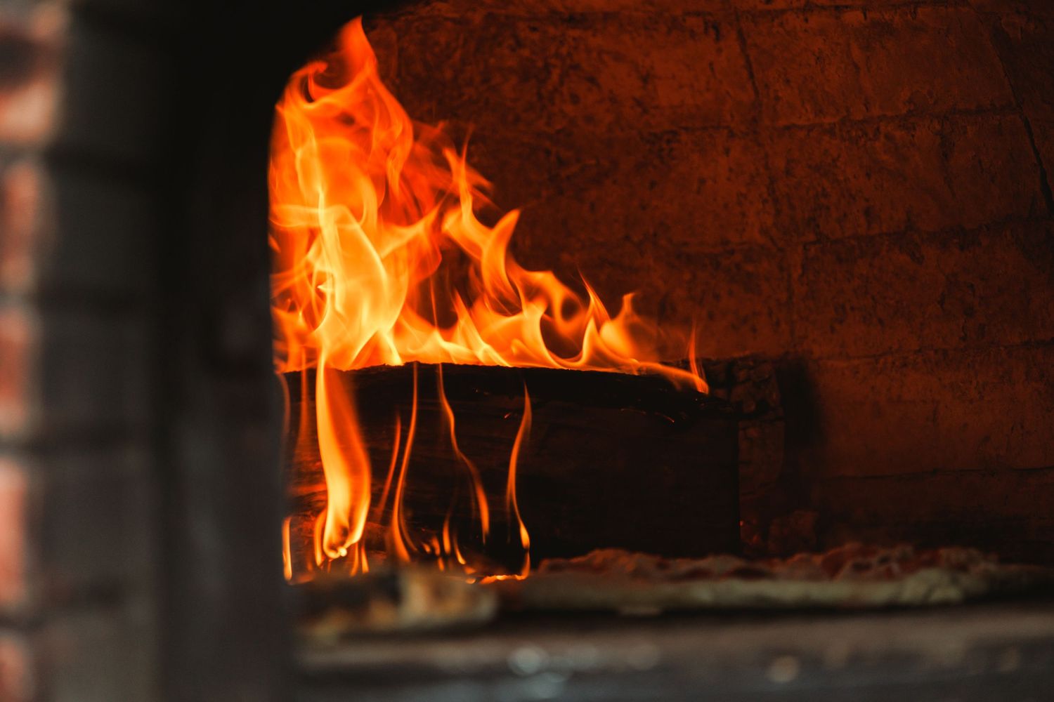 Bright orange flames burning in a brick oven or fireplace.