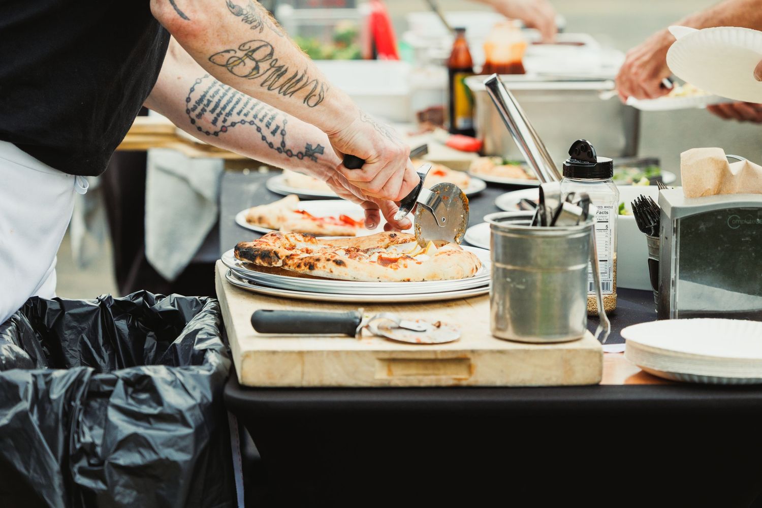 Hands preparing food on wooden cutting boards in a professional kitchen setting.