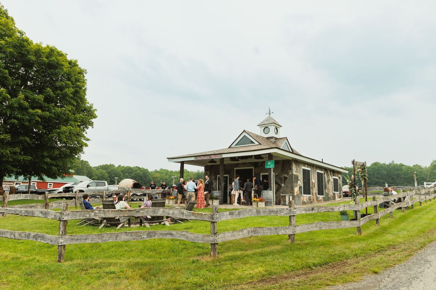Panoramic view of a rural cemetery with white chapel and split-rail fencing on rolling hills.
