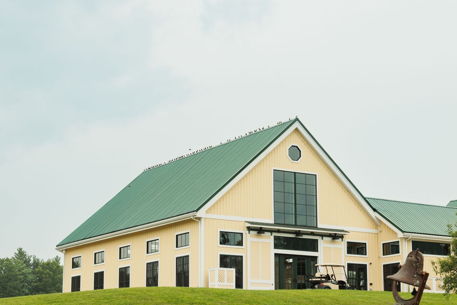 Modern beige and green agricultural or industrial buildings against a cloudy sky.