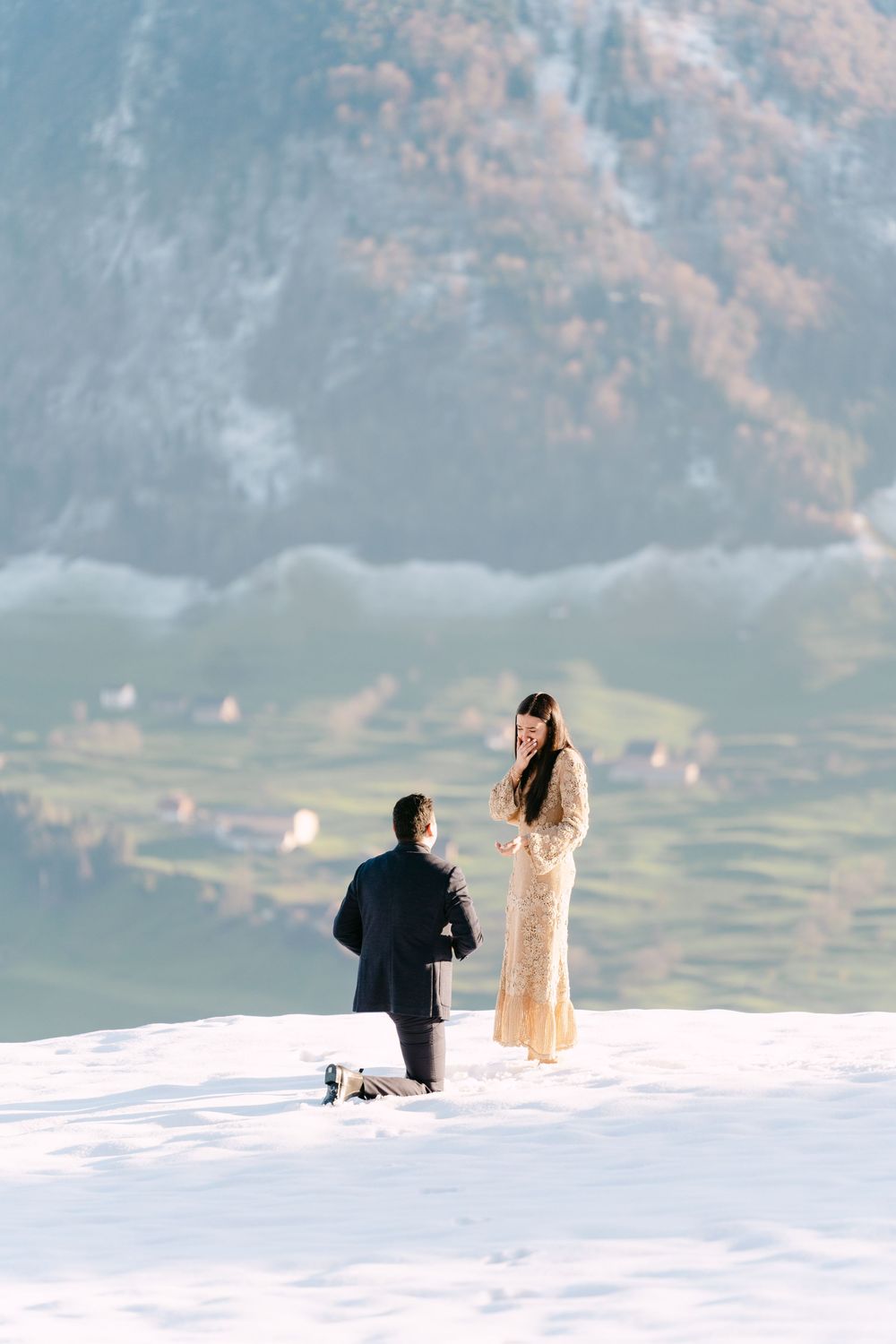 A romantic surprise marriage proposal scene unfolds in the snow with mountain views and soft winter lighting in the background.
