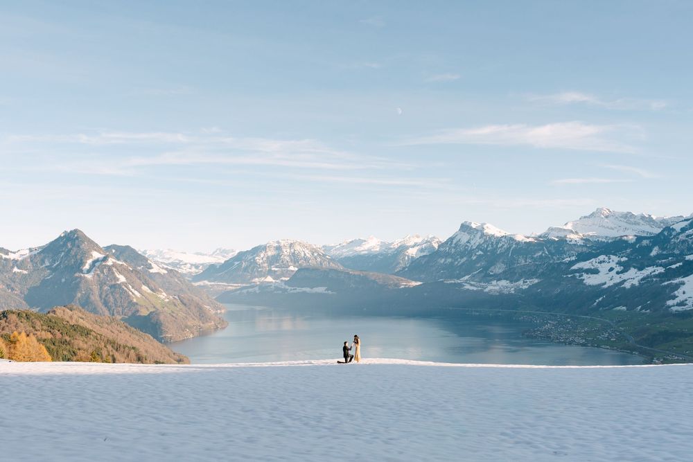 A proposal at Villa Honegg above Lucerne panoramic view of snow-capped mountain peaks reflecting in a pristine alpine lake under a blue sky.