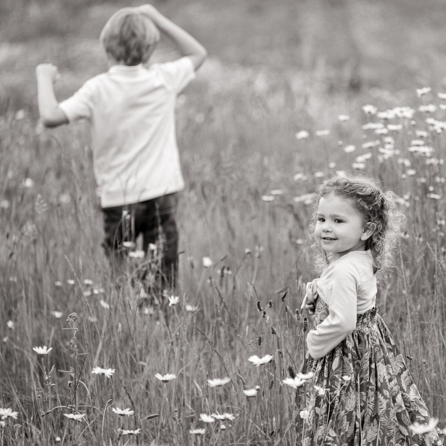 Two children running through an axe-eye daisy field.
