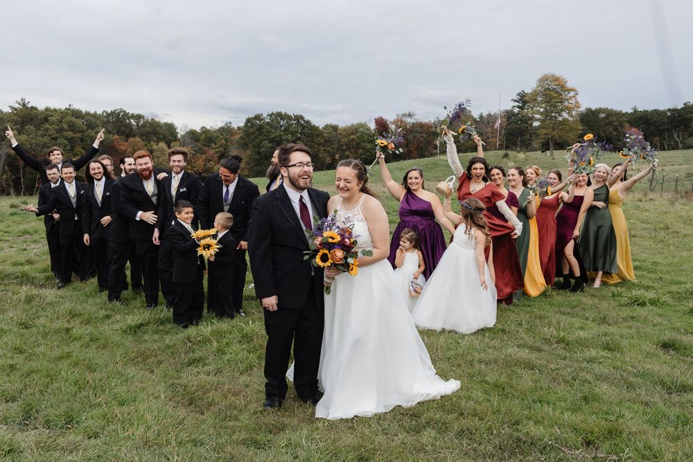A laughing wedding party poses in a farm field for bridal party photos in southern New Hampshire. Seacoast, Vermont Wedding photographer