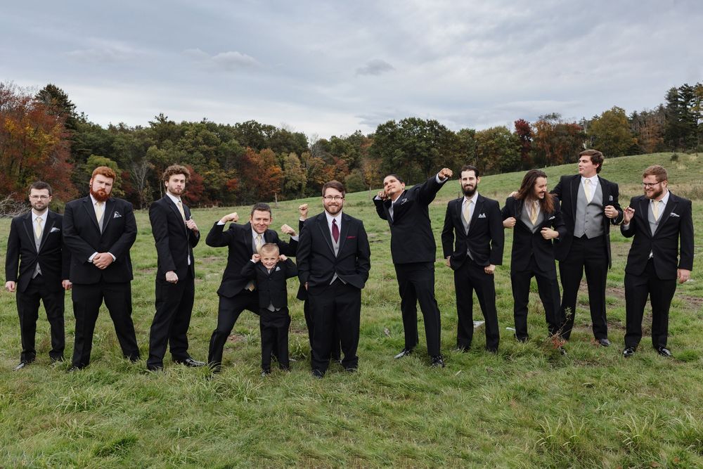 Groomsmen pose in a silly way for bridal party photos in a field. Vermont, Maine wedding photographer, Berkshires wedding photographer,