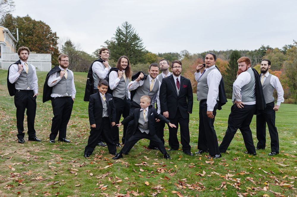 Groomsmen pose in a silly fashion for bridal party photos at a country wedding in New Hampshire. Farm, country wedding photographer Vermont