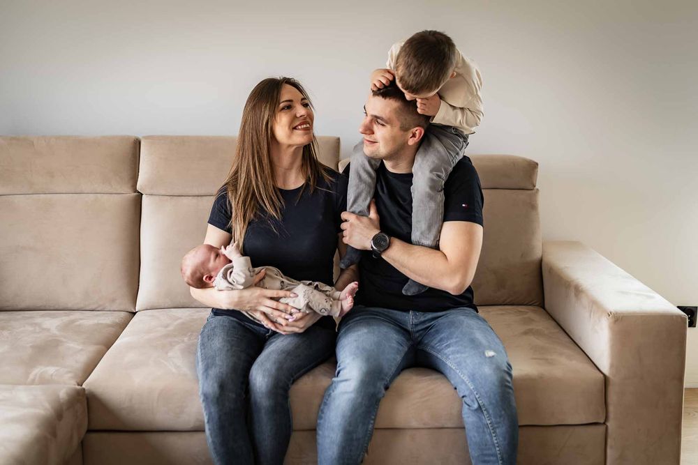 A family shares joyful moments together while relaxing on a beige couch.