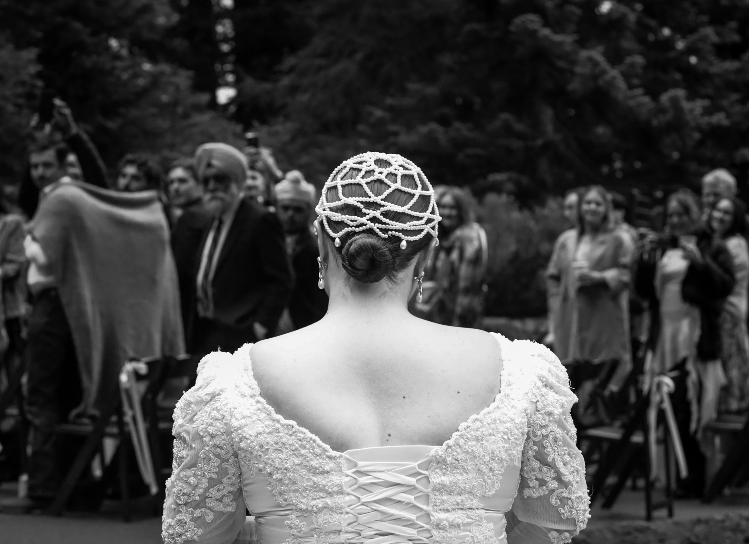 Black and white wedding photos showing bridal dress details with ornate lace and pearl embellishments from behind.