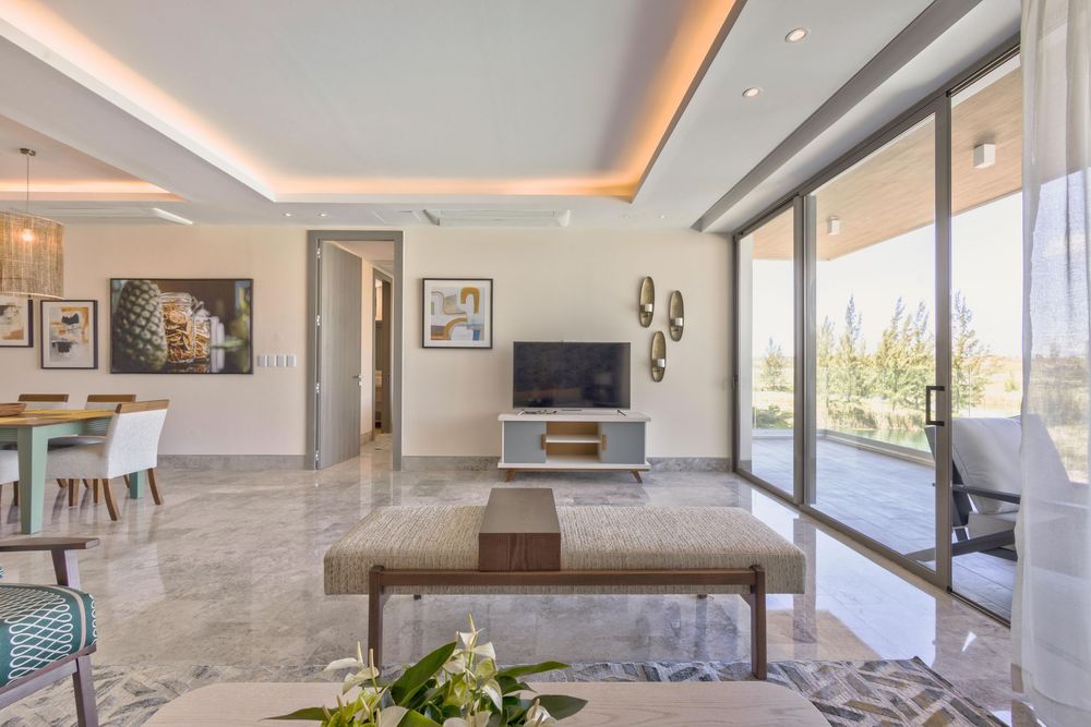 Modern luxury living room with marble floors, floor-to-ceiling windows, TV unit, and open-plan dining area with natural light.