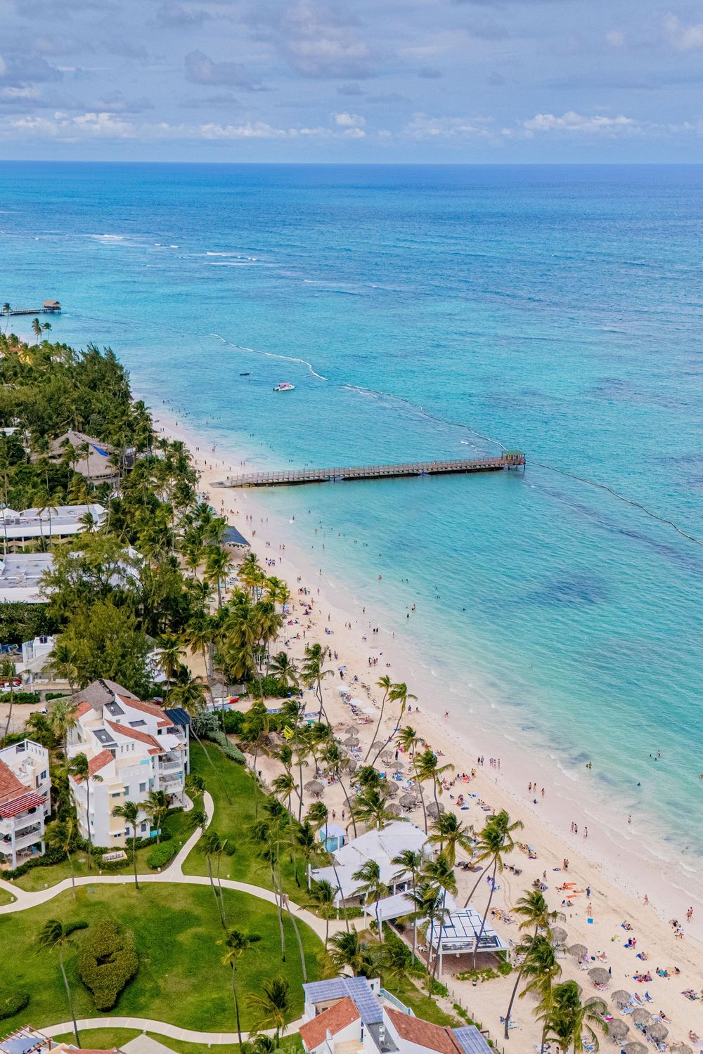 Aerial panoramic view of a pristine Caribbean beach with turquoise waters, white sand, and beachfront properties. Bavaro Beach
