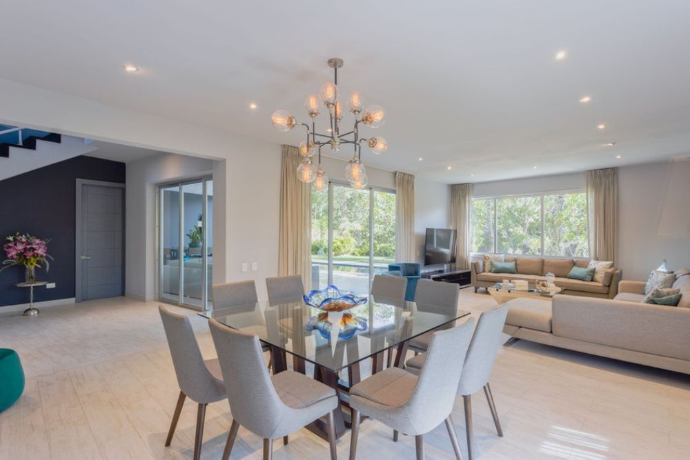 Modern open concept living and dining area with recessed lighting, light wood floors, and contemporary furnishings. Real State.