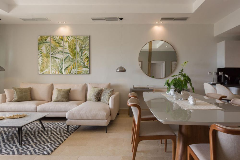 Bright contemporary living space with beige sofa, abstract wall art, and geometric area rug in neutral tones. Real State.