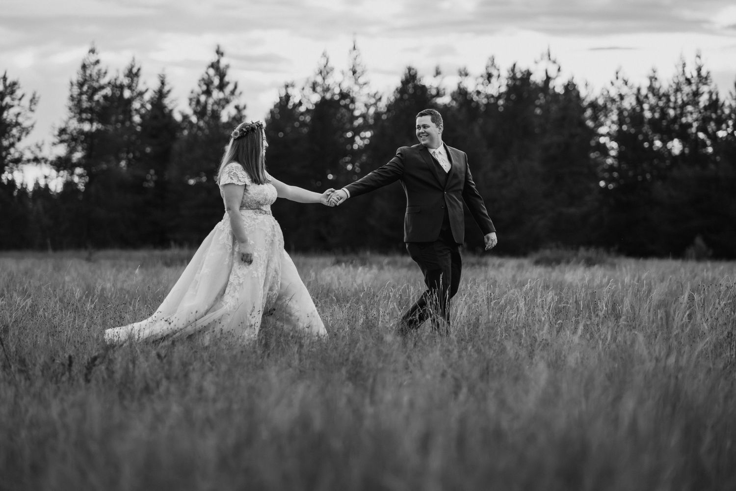 A couple shares an intimate moment in a field during their wedding ceremony in black and white.