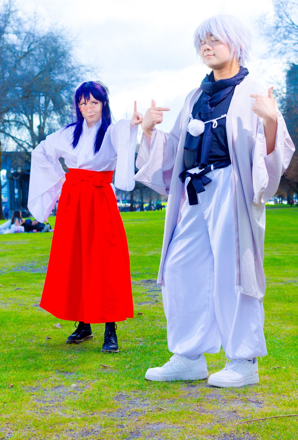 Cosplay photoshoot in a park featuring traditional Japanese-inspired outfits with red hakama and white robes.