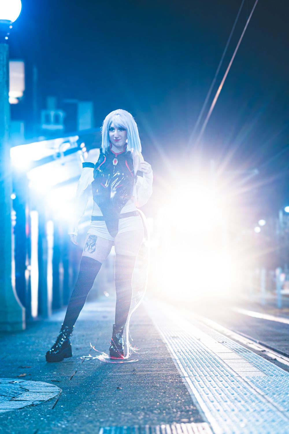 Dramatic nighttime street photography with bright backlighting and silhouetted figures on textured pavement.