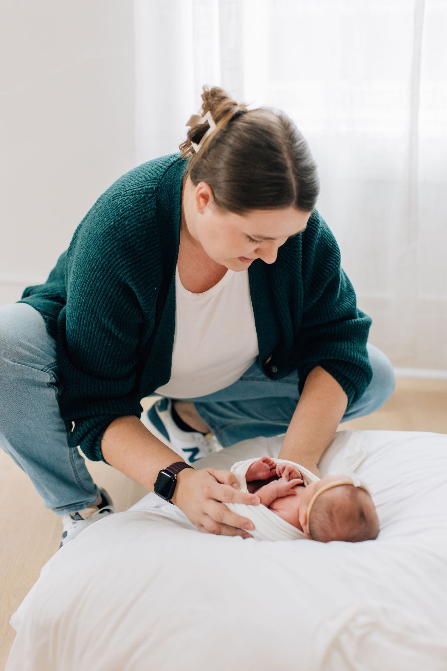 Series of lifestyle newborn photography shots showing tender moments with baby on white bedding.