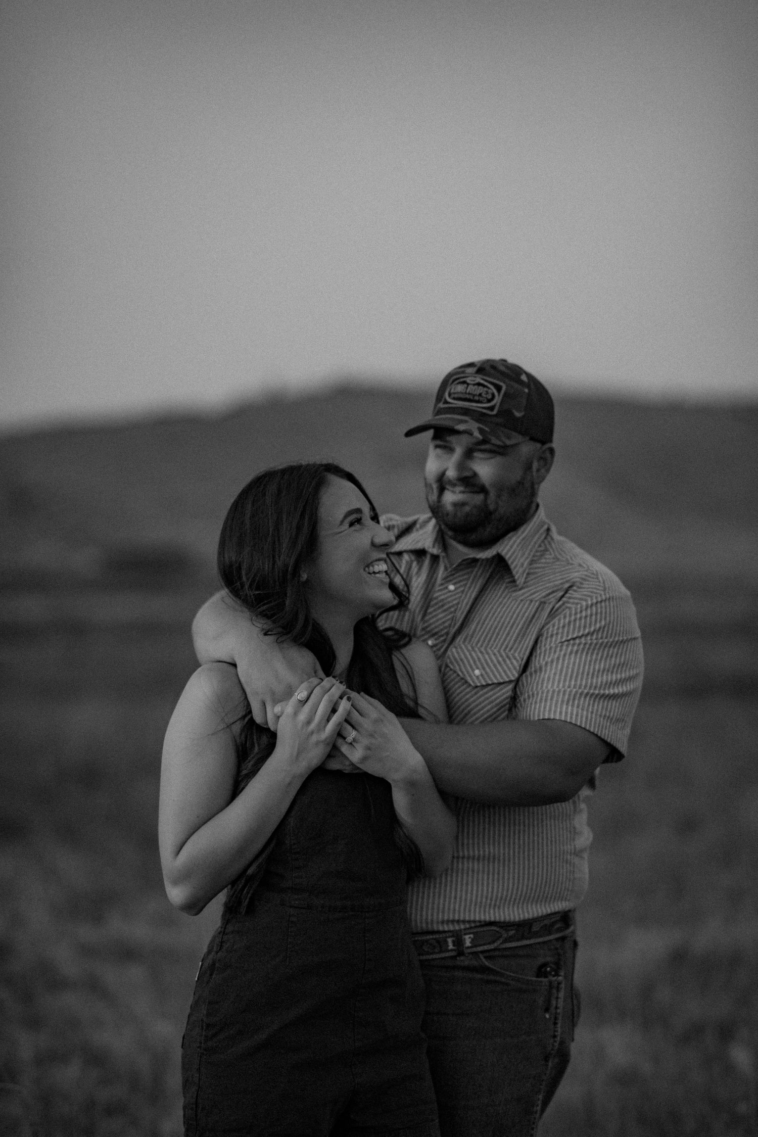 A couple shares a tender moment together in a field during a black and white photo session.