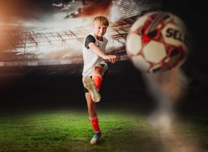 Soccer player kicking a ball on a grass field during a dramatic sunset with motion blur effects.
Best child's photographer