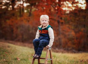 Small child sitting on step-ladder smiling at camera with fall scenery in the back

Best child photographer, Peoria, IL.