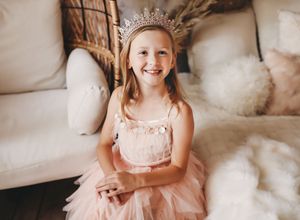 A delicate pink dress with lace details and pearls creates an ethereal look against a soft neutral background.
Best child's photographer