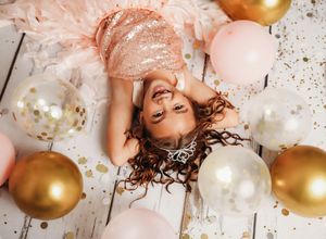 Decorative pink and gold balloons arranged on a light wooden surface with scattered confetti.
Best child's photographer in Illinois