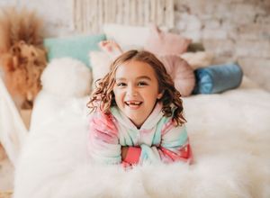 Kid laying on her stomach soft bed and smiling up at camera

Best children's photographer, Central Peoria, IL.