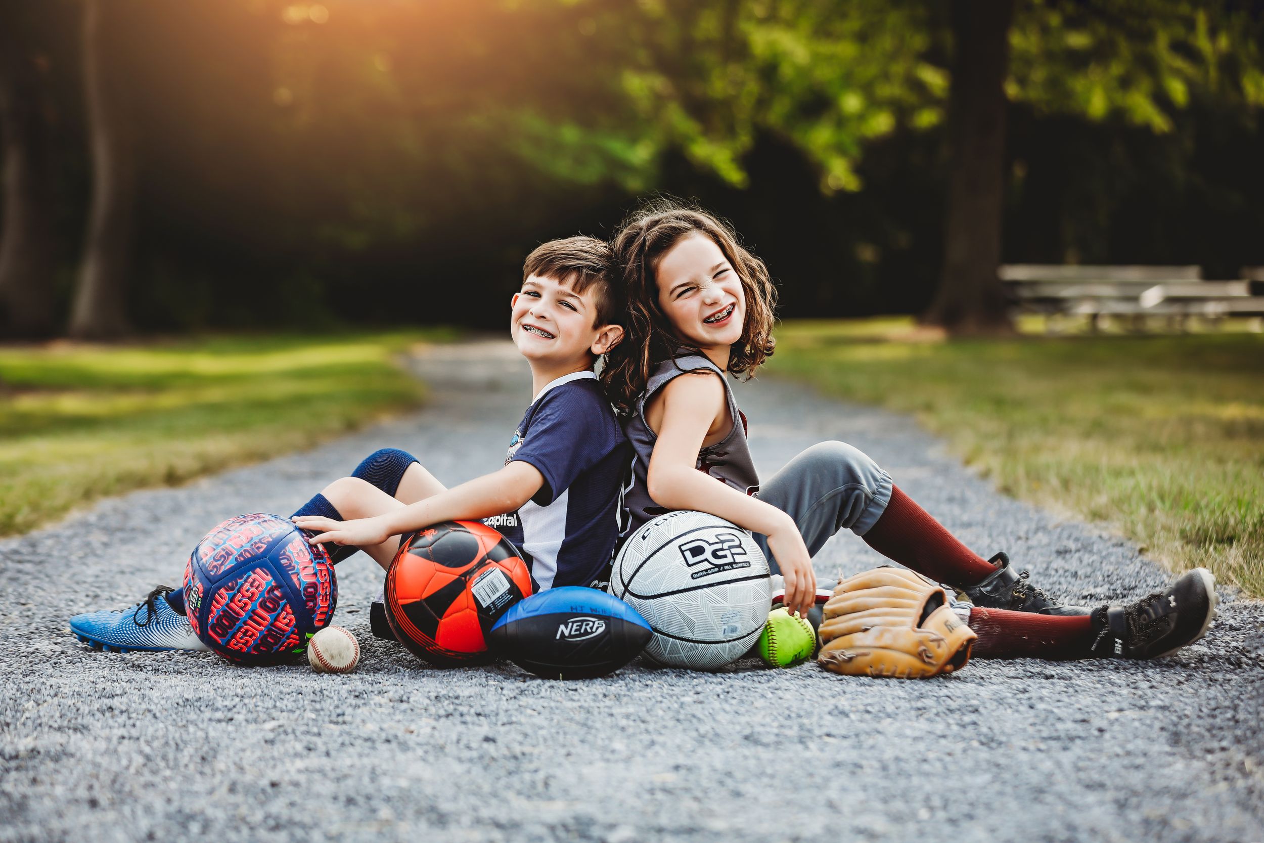 Two children sitting back to back smiling at camera with sports balls around them

Best athlete photographer, Peoria, IL.