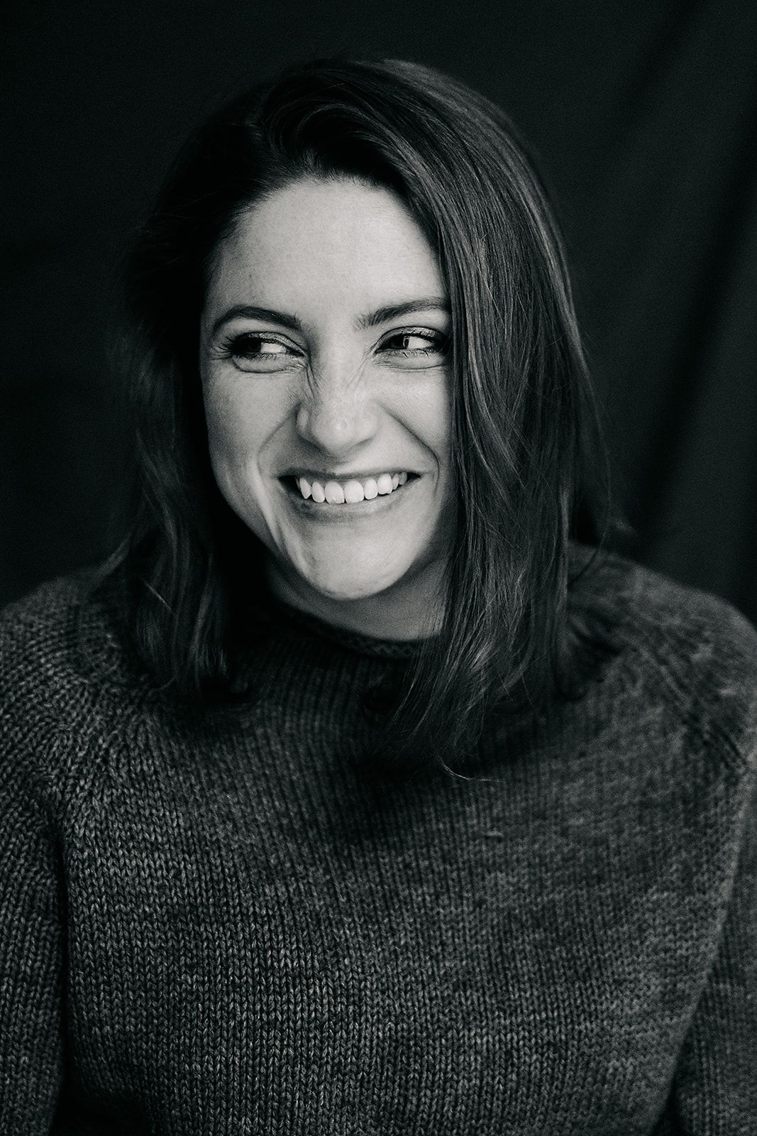 Black and white portrait series showing joyful expressions and genuine laughter while wearing a cozy sweater.