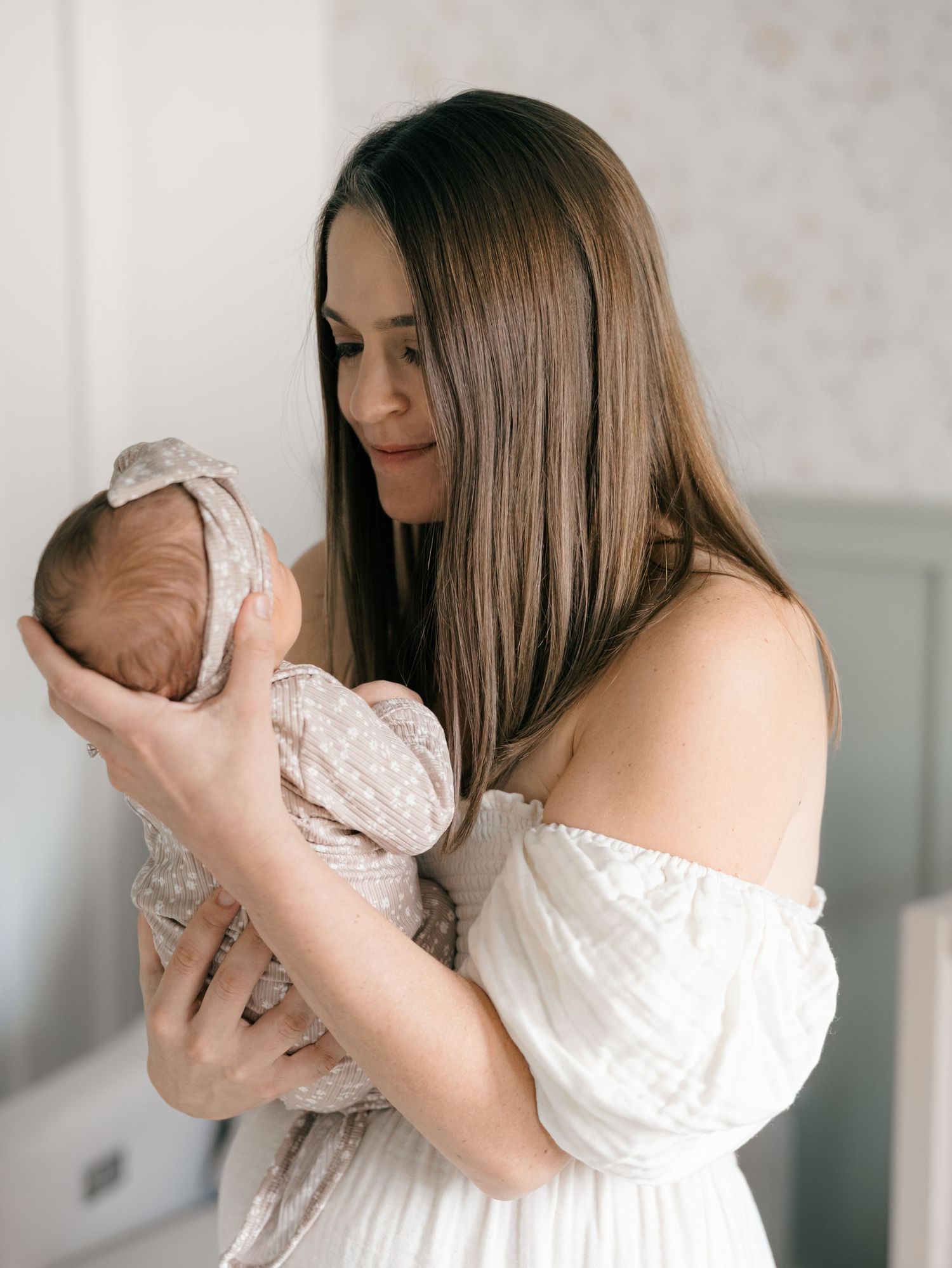 Close up image of mother holding her newborn girl in a sage and pink nursery in middletown NJ.