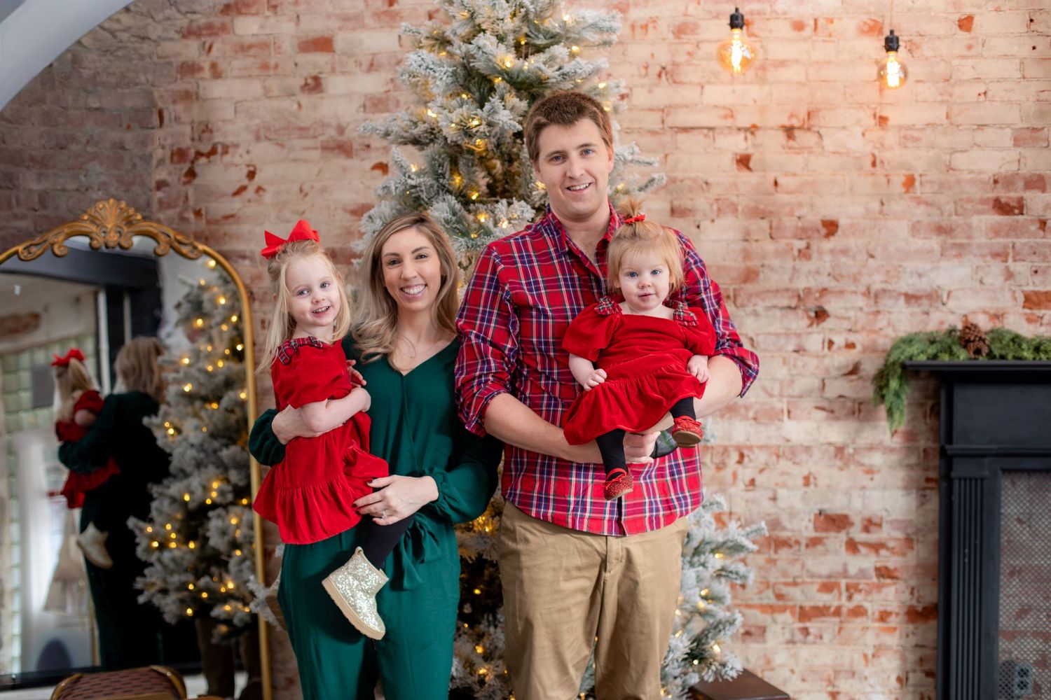 Cincinnati family Christmas photos with parents and two daughters sharing warm smiles in a cozy holiday studio setting.