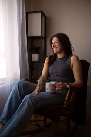 A casual moment by the window shows someone relaxing in a rocking chair with a coffee mug.