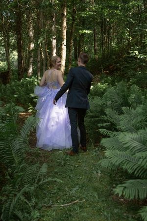 A couple walking through a lush forest setting with ferns and greenery for wedding photos.